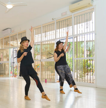 Young Dance Instructor Leads A Lively Charleston Class Of Older Women, All Sporting Top Hats And Holding Dance Canes