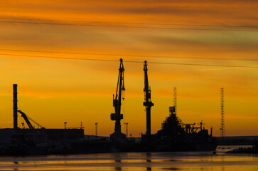 Big plant. Port cranes. Shipyard. Yellow sunset. industrial landscape
