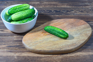 fresh cucumbers in a ceramic bowl on a wooden table. Healthy food concept - 588486877