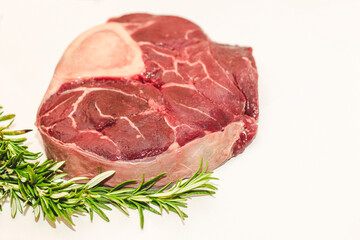 Fresh piece of meat large beef steak on the bone ossobuco with rosemary sprig.