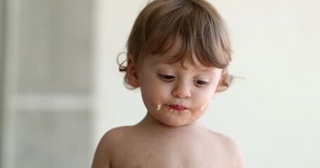 Messy baby infant boy covered with food looking for napklin