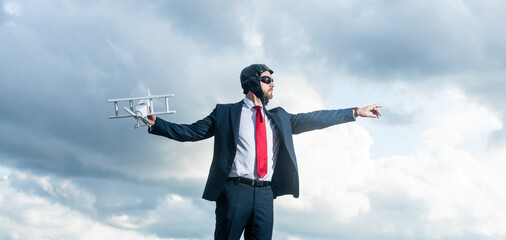 employee in suit and pilot hat launch plane toy on sky background