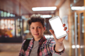 Schoolboy showing mobile phone in school corridor