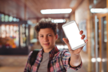 Schoolboy showing mobile phone in school corridor