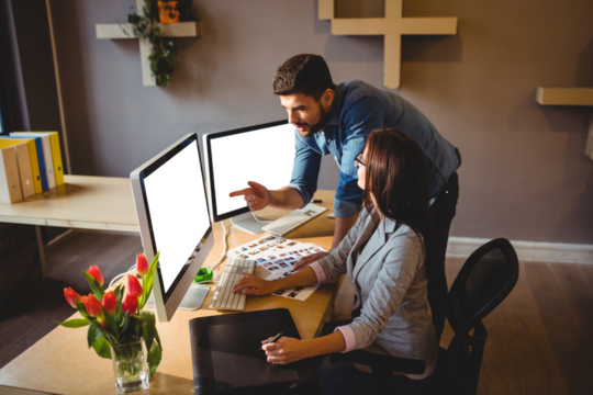 Graphic designer pointing at monitor