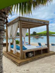 Beach cabanas overlooking the Caribbean Sea. Relax in the shade. Beach, sand, umbrellas, loungers, curtains, palm trees, beach beds. Adrenaline Beach, Labadee, Haiti private resort by Royal Caribbean.