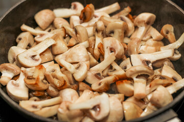 Chopped champignon mushrooms are fried until golden brown in a pan.
