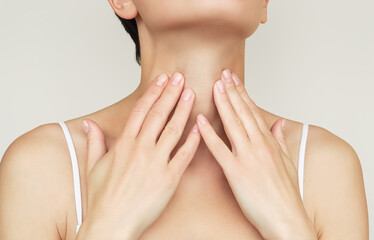 a woman holds her throat with her hand because of problems with her throat and thyroid gland