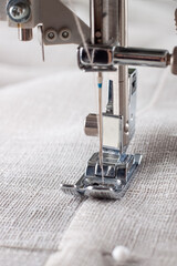 Modern sewing machine presser foot with linen fabric and thread, closeup. Sewing process clothes, curtains, upholstery. Business, hobby, handmade, zero waste, recycling, repair concept