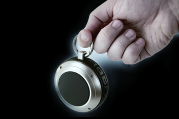 Portable wireless speaker for music in hand on a dark backlit background. Background for audio...