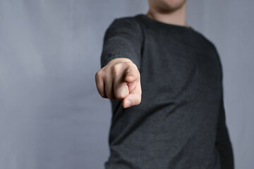 Gesture pointing at you from the picture with a young man's index finger. Calling or pointing sign, pointing finger