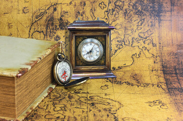 Classic round compass and old vintage clock and book on old vintage map