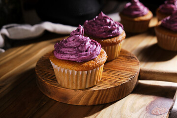Fresh muffins with blueberry cream on a wooden desk