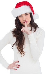 Festive brunette in santa hat keeping a secret