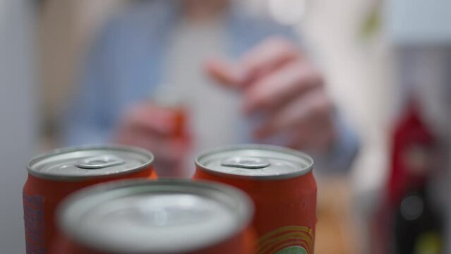 Products, A young man Takes a metal can of a drink from the refrigerator shelf In a living room. Young gentleman takes out goods from the refrigerator in the place for bottles and cans, restocking
