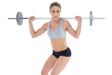 Strong female crossfitter lifting barbell behind head looking at camera