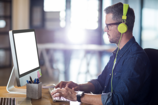 Side view of man with headphones working on computer