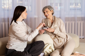 An elderly woman in excellent shape offers a chocolate to her granddaughter or a young girl and...