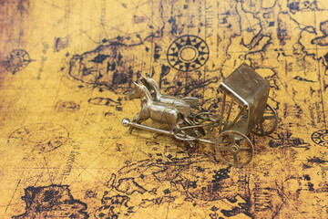 Bronze figurine with horses on background of old vintage map of world