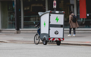 Naklejka premium Un vélo électrique cargo dans la ville pour transporter et livrer des colis. 