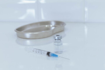 Syringe and glass bottle with metal tray on white background