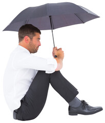 Businessman sitting on the floor with black umbrella