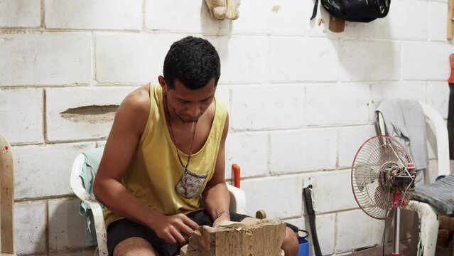 young latino man carving a figure in wood