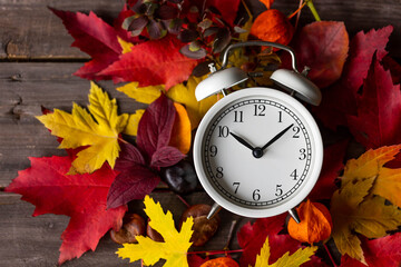 Fall winter time change concept. Autumn composition with retro alarm clock, bright yellow and red...