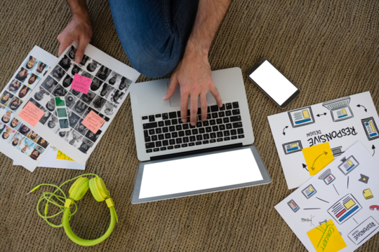 Cropped hands of designer with collage using laptop