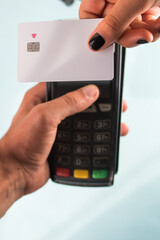 Hand with black painted nails holding a credit card on a dataphone