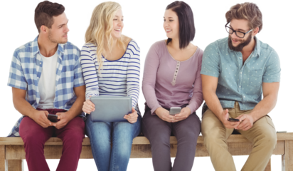 Smiling business people holding electronic gadgets while sitting on desk 