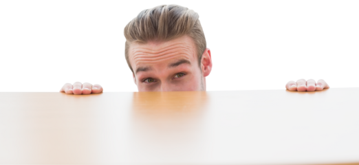 Portrait of businessman peeking behind the desk