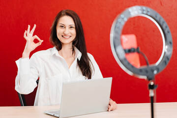 a brunette woman works at the computer and conducts a live broadcast 