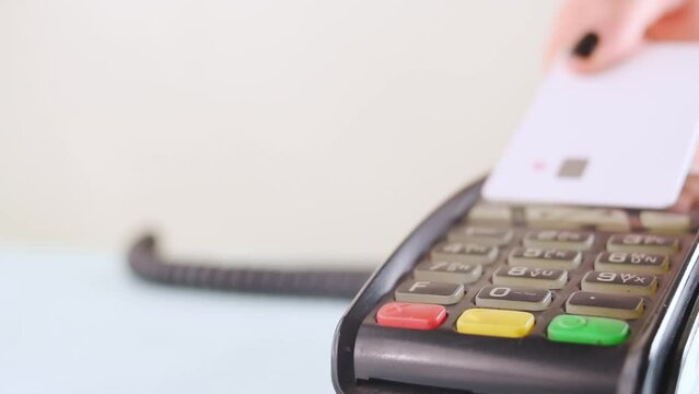 Hand with black painted nails paying with a credit card on a dataphone