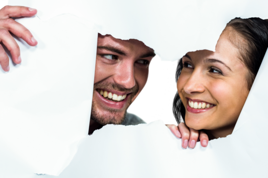 Couple peeking through torn paper 
