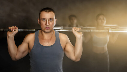 Fototapeta na wymiar Portrait of sporty man doing exercises with barbell to strengthen body muscles in modern gym during group workout. Physical activity and bodybuilding concept..