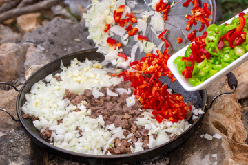 man prepares food on a campfire in a clearing near the mountains. Stalker, survive in the jungle