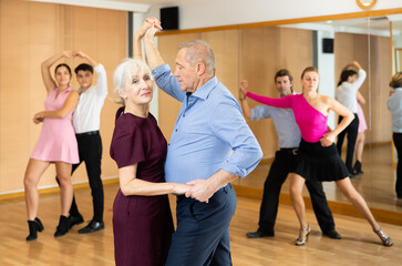 Spirited old pair training waltz dance during workout session. Pairs training ballroom dance in hall