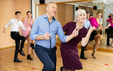 Cheerful elderly couple practicing ballroom dances in ballroom - obrazy, fototapety, plakaty