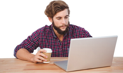 Serious hipster holding disposable cup working on laptop