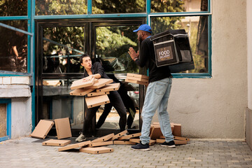 Confused woman catching falling pizza boxes stack, scared courier standing in front of office...