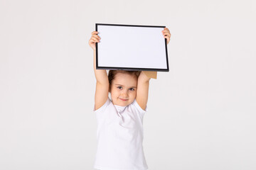 portrait of baby girl holding white drawing Board on white background, young girl is holding a drawing board in her hands. white isolated background