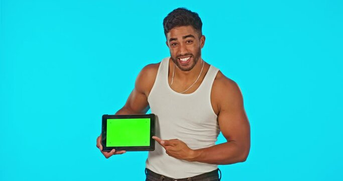 Face, green screen and man with tablet pointing in studio isolated on a blue background. Technology, muscle flexing and happy male model with product placement, marketing or advertising for mockup.