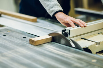 Close up picture of a workman cutting furniture parts on a cutting machine at his workshop.