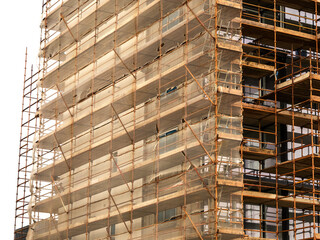 Side of a new building in scaffolding and safety nets. Construction site safety measures. Developing commercial or residential property. Growth concept.