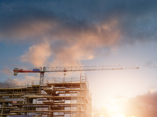 New building construction in scaffolding and tall crane. Commercial or residential property. Tall...