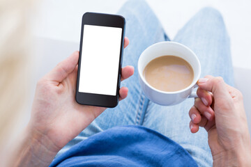 Woman using her mobile phone and holding cup of coffee