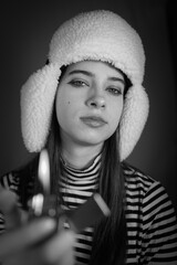 Portrait of a girl of model appearance. Black and white portrait of a young woman in a winter hat and striped jacket.