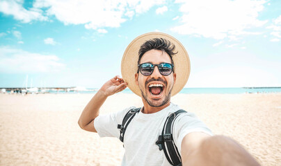 Handsome young man taking selfie picture at beach summer vacation - Smiling guy having fun walking...