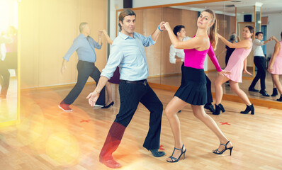 Spirited middle-aged pair training Latino dance during workout session. Pairs training ballroom dance in hall